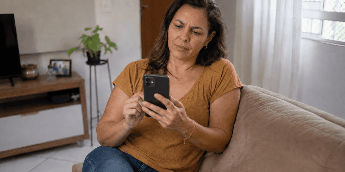 Mulher consultando o celular para verificar informações sobre uma dívida caducada.