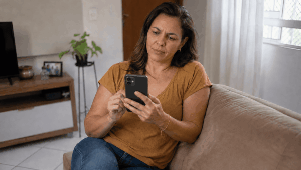 Mulher consultando o celular para verificar informações sobre uma dívida caducada.
