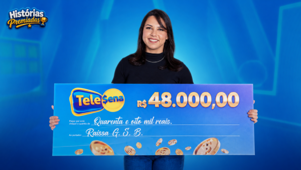 Raissa, ganhadora da Tele Sena, segurando o cheque que representa o prêmio de R$ 48 mil.