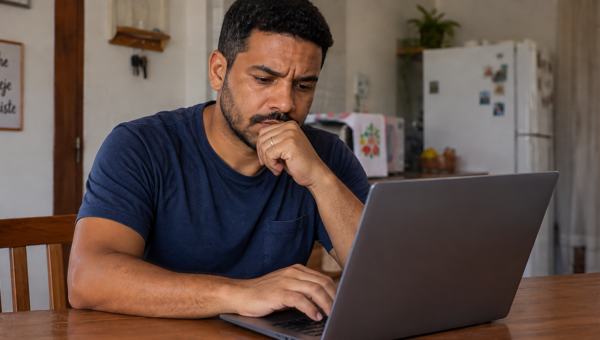 Homem consultando informações sobre protesto de dívida no notebook em casa.